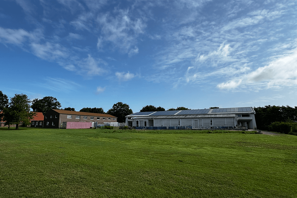 FOUR PACK Firmengebäude mit Photovoltaikanlage auf dem Dach und grüner Wiese davor.