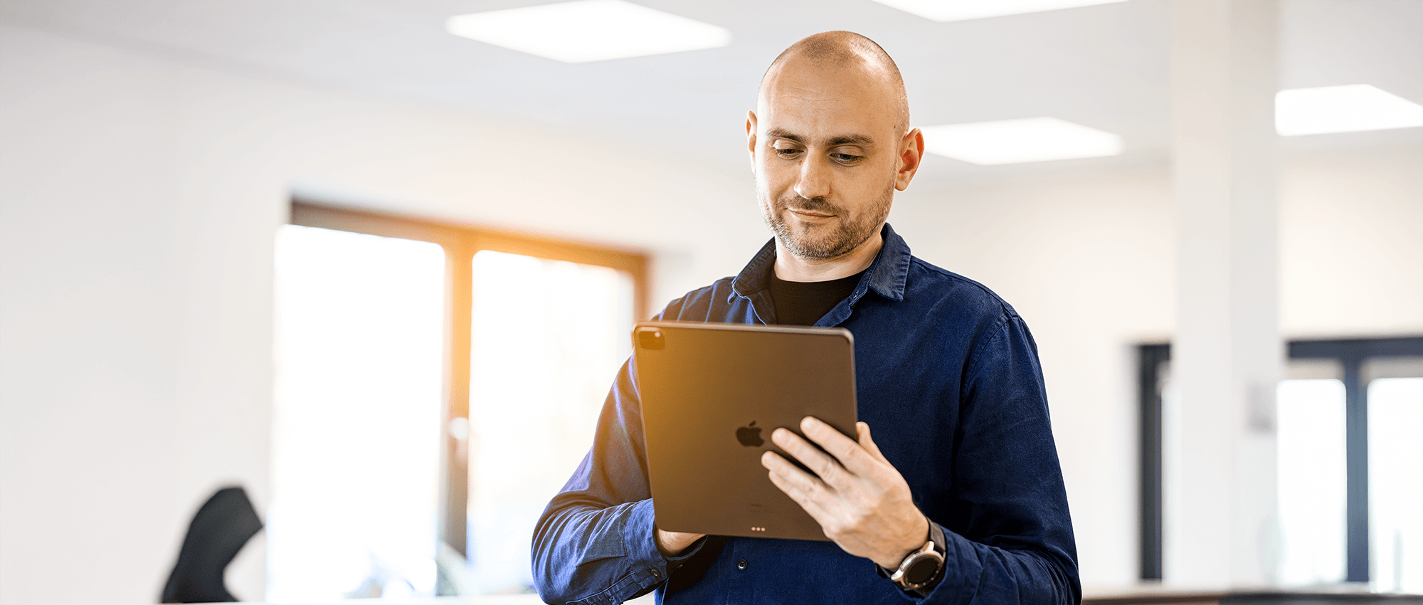 Mitarbeiter von FOUR PACK im Büro schaut auf ein iPad.