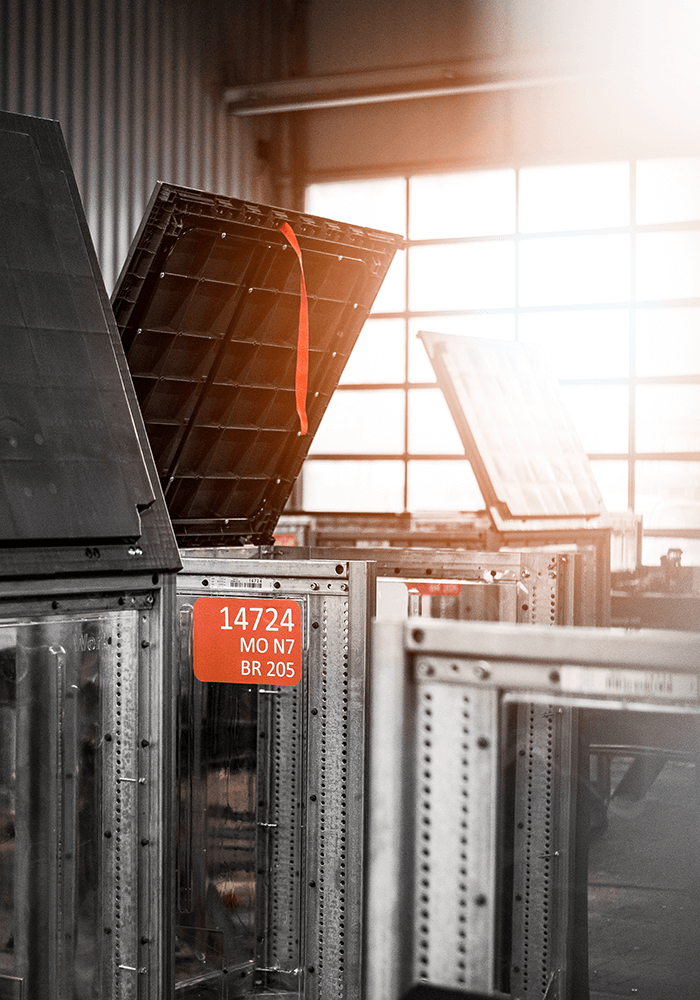 Stack of metal boxes with red labels in an industrial hall.