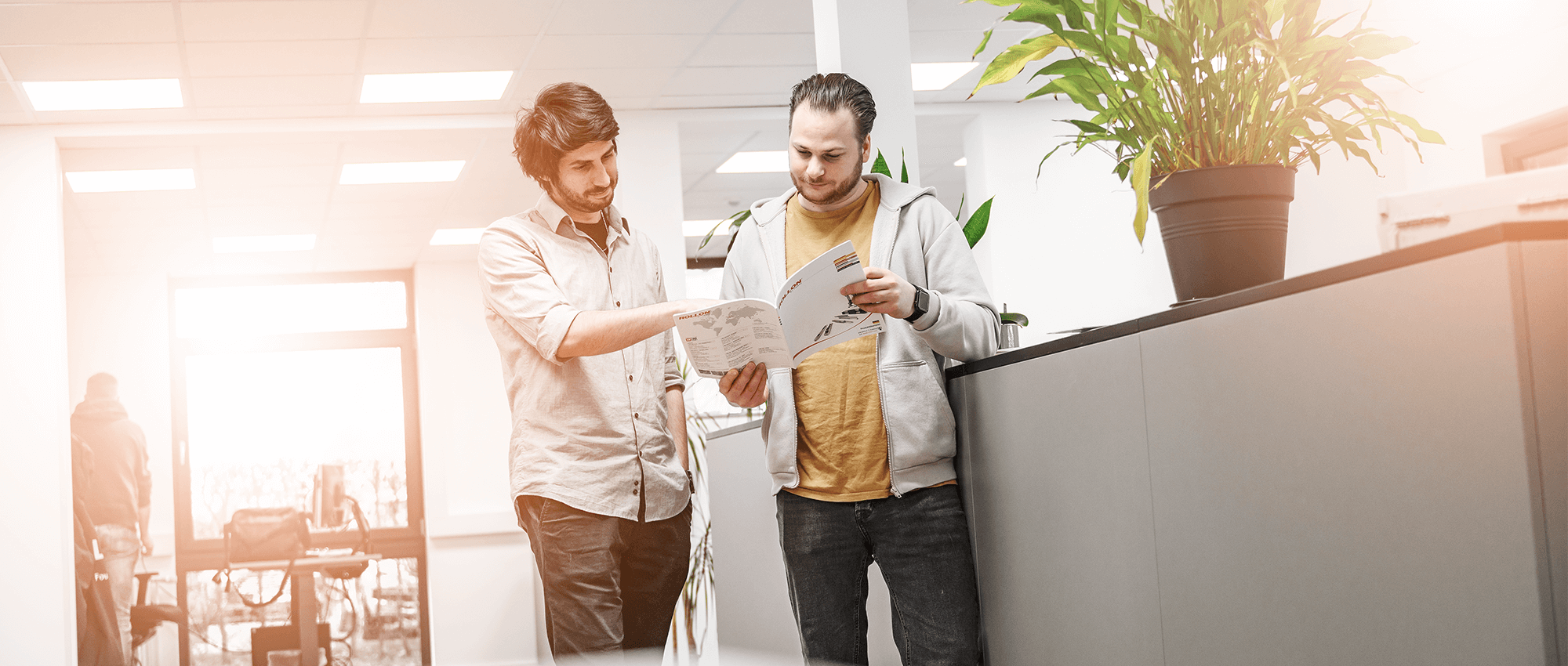 Zwei Mitarbeiter im Büro von FOUR PACK schauen gemeinsam in Unterlagen.