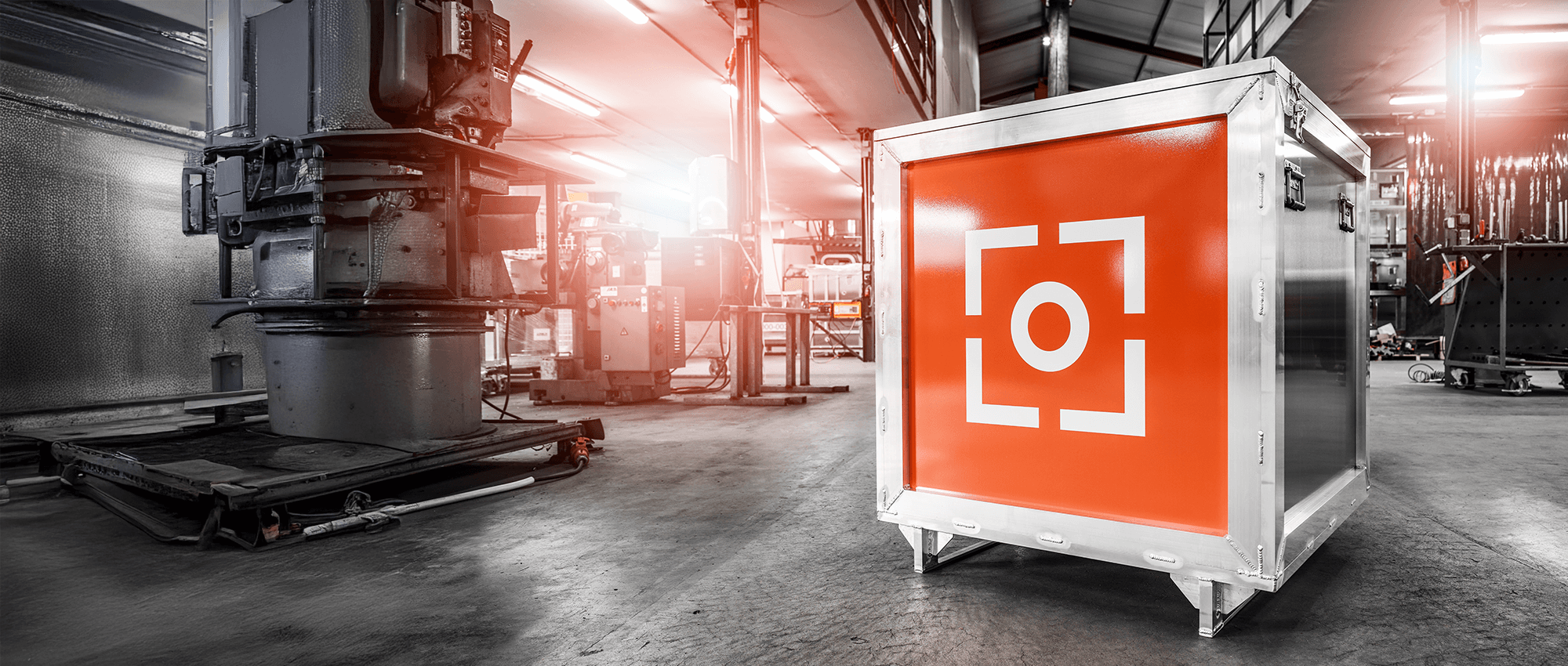 Silberner Transportcontainer mit oranger Front und FOUR PACK Logo in einer Industriehalle.