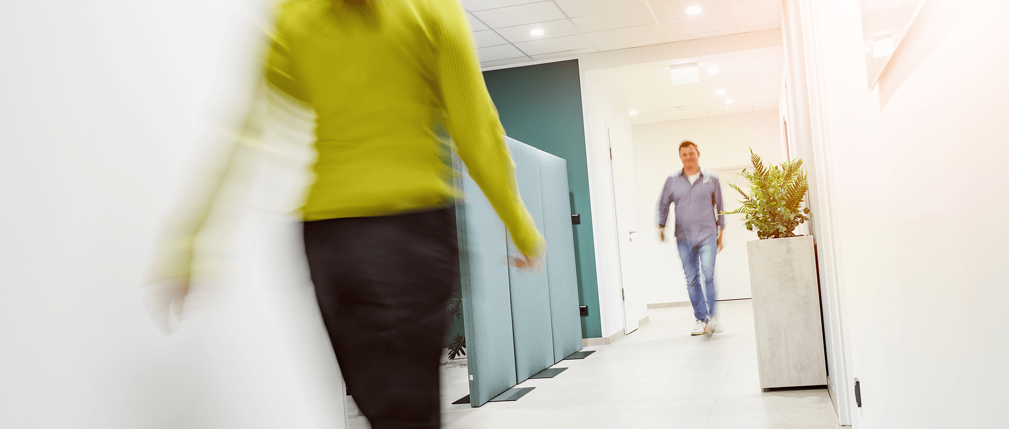 Zwei Mitarbeiter begegnen sich im Büroflur von FOUR PACK.