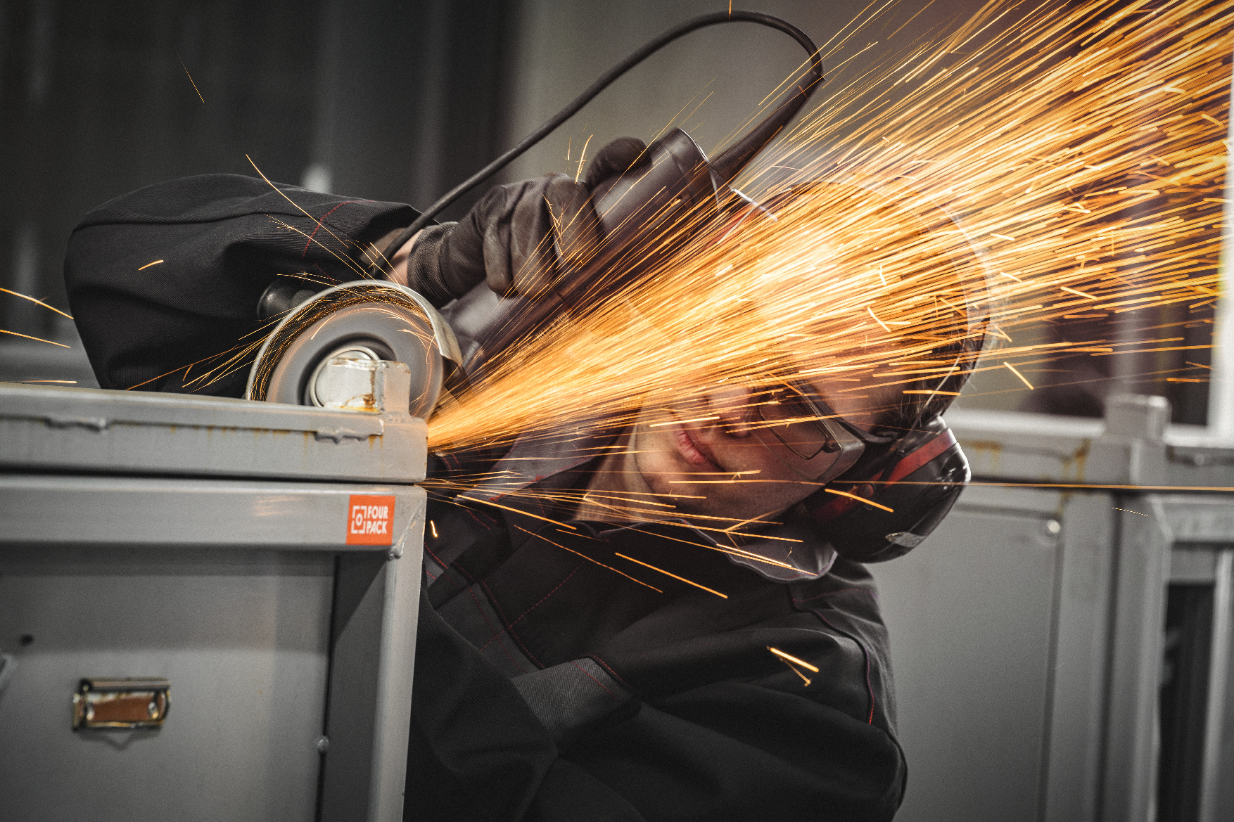 Hände mehrerer Personen über Bauplänen mit einer orangefarbenen FOUR PACK Mappe.